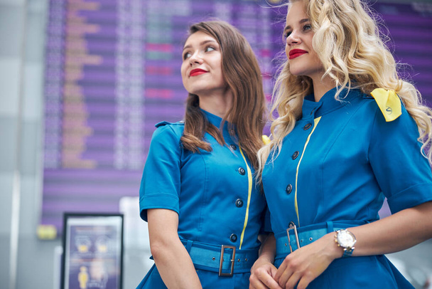 Affascinanti assistenti di volo in piedi nel terminal dell'aeroporto - Foto, immagini