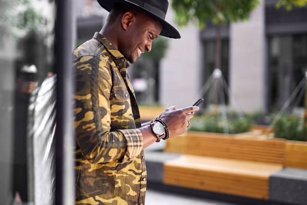fashionable african man hold mobile phone in hands outdoors, chatting - Valokuva, kuva