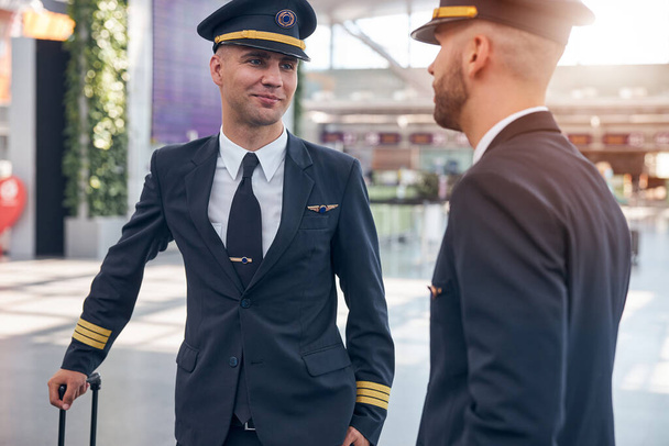 Handsome young pilots waiting for flight at airport - Foto, afbeelding