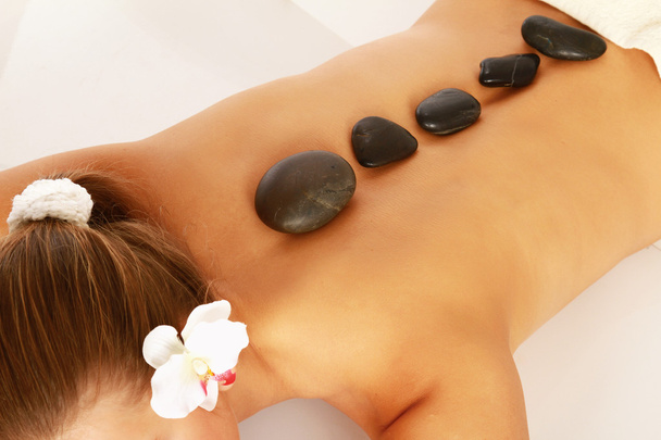 Woman receiving a therapy with hot stones in spa center - 写真・画像