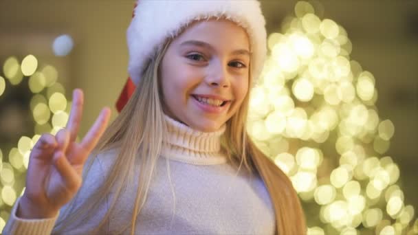 Het leuke meisje glimlachend op de kerstboom achtergrond. slow motion - Video