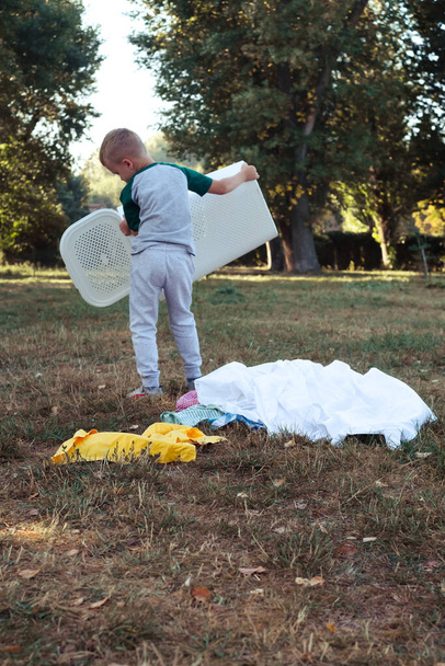 the kid throwing clothes out of the basket. outdoor. High quality photo - Photo, image