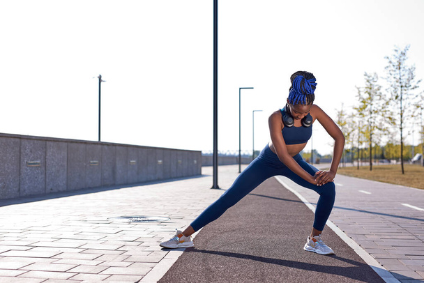 athlete afro woman stretching hamstring leg muscles during outdoor running workout - Fotografie, Obrázek