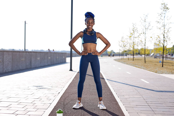 portrait of smiling african woman standing outdoors, after sport exercises - Photo, Image