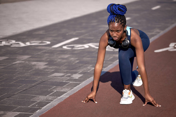 athletic african american girl stands at the start, about to run - 写真・画像