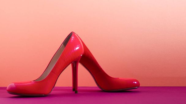 Elegáns klasszikus cipő közelkép. Élénk rózsaszín magas sarkú cipő. Rózsaszín és ibolya háttér. - Fotó, kép