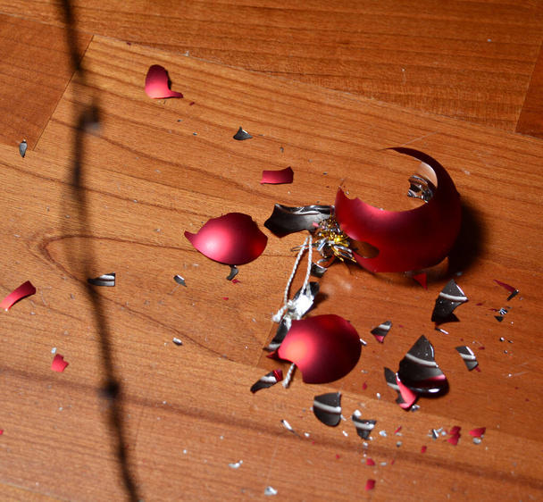τυχαία σπασμένη κόκκινη μπάλα του νέου έτους, σε ξύλινο δάπεδο και προετοιμασία για τον εορτασμό του νέου έτους. αντίγραφο χώρου. - Φωτογραφία, εικόνα