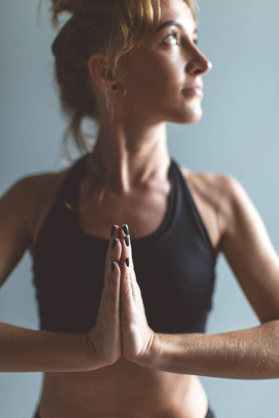 Woman practicing yoga pose namaste, gray wall background, selective focus. copy space. - Fotoğraf, Görsel