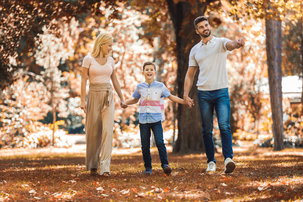 Happy parents have fun with their son in autumn park. - Photo, Image