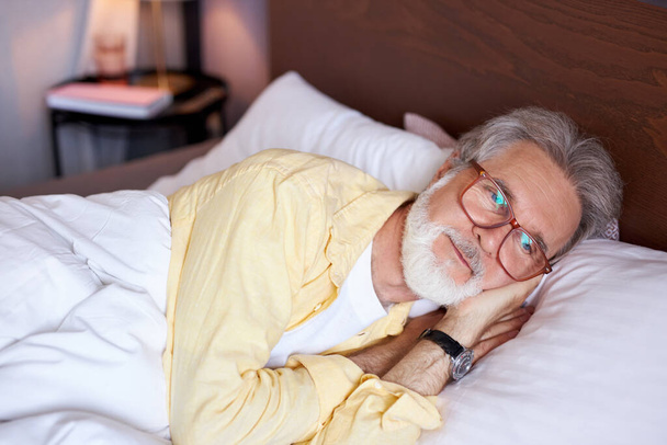 thoughtful senior man lie on bed at home - Фото, зображення