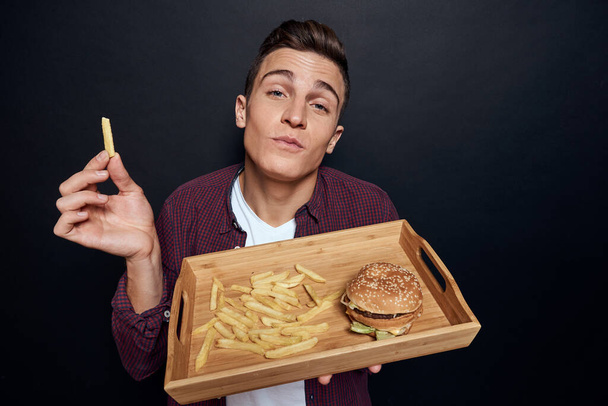 hombre sosteniendo paleta de madera con comida rápida en sus manos dieta hambre de alimentos estilo de vida oscuro fondo - Foto, Imagen