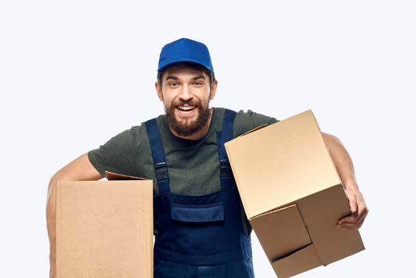 Un hombre con un uniforme de trabajo con una caja en las manos entrega trabajo de transporte - Foto, imagen