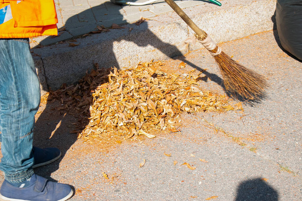 Parkta sonbahar çalışması. Düşen izinlerin temizlenmesi. Sonbahar ve baharda dökülen yaprakları temizleyen temizlikçiler.. - Fotoğraf, Görsel
