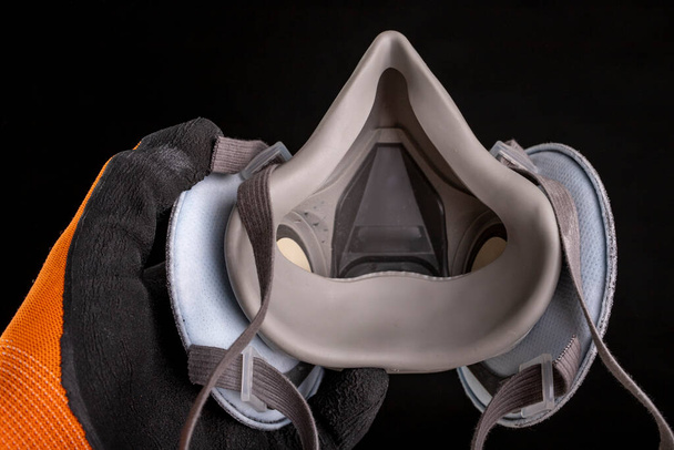Dust mask in hand. Respiratory protection accessories. Black background. - 写真・画像