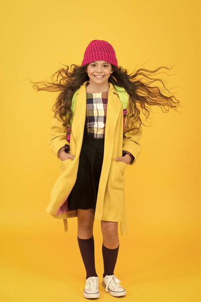 School life. Fancy schoolgirl. Girl little fashionable pupil wear knitted hat and jacket. Modern outfit. Adorable schoolgirl winter outfit. Schoolgirl daily outfit with backpack. Fashion accessory - Φωτογραφία, εικόνα