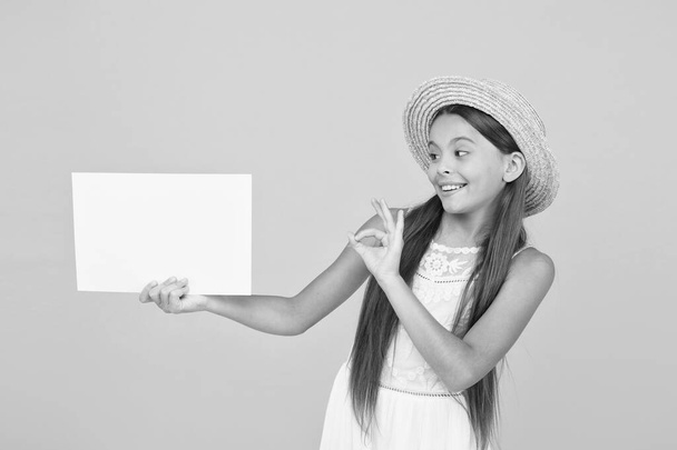 summer shopping sales. happy little girl hold blank paper. copy space. Hot vacation time. travel to warm countries. kid spring fashion. girl in straw hat. advertisement. kid traveler - Foto, afbeelding