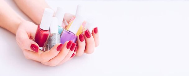 Лак для ногтей. Искусство маникюра. Разноцветные Nail польские бутылки в руках. Стильные красные ногти - Фото, изображение