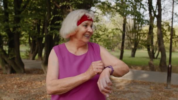 Senior sport runner vrouw met behulp van slimme horloge, tracking afstand, het controleren van de pols na fitness workout - Video