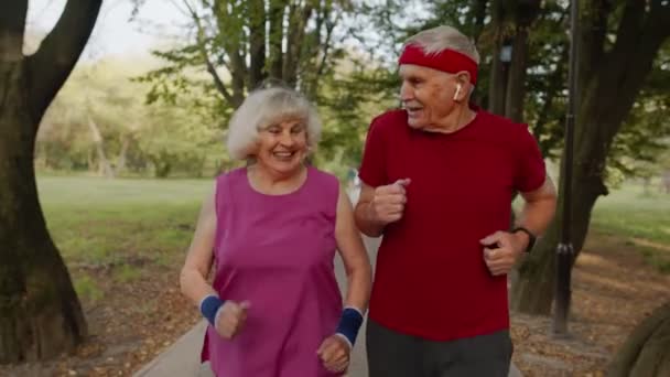 Aktywna starsza para robi poranne ćwiczenia kardio. Mężczyzna, kobieta biegająca w parku miejskim. - Materiał filmowy, wideo