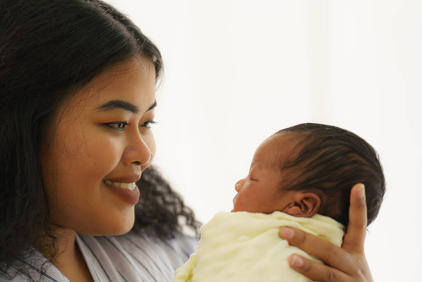 mixed race african american and asian mother holding her newborn baby with happy face - Fotografie, Obrázek