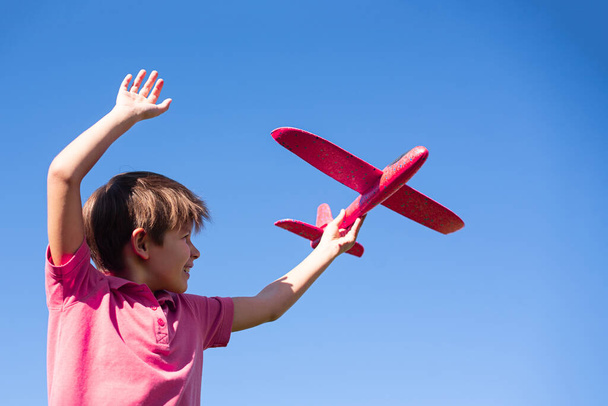 Çocuk gökyüzüne karşı kırmızı bir uçakla oynuyor. Mutlu Çocuk Oyunları - Fotoğraf, Görsel
