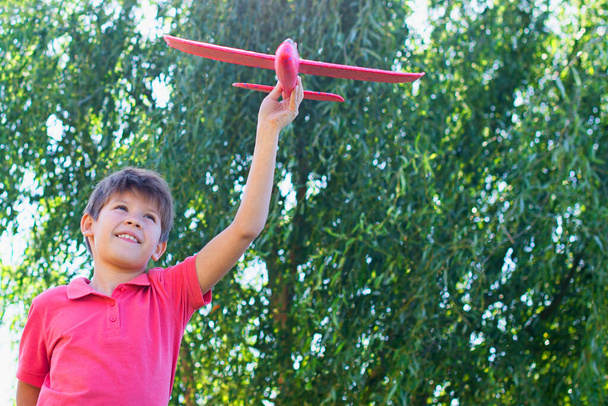 boy playing with a red plane against the sky. Happy childrens games - Photo, image