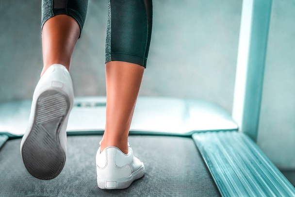 Indoor runner legs is walking slowly on the treadmill for light exercise closed up shot. - Valokuva, kuva