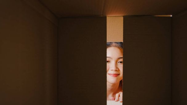 Захоплена азіатська молода жінка розпаковує величезну коробку з картонними коробками і дивиться в будинок. Щаслива жінка-клієнтка задоволена тим, що її замовили. Доставка і онлайн-магазин концепції. - Фото, зображення