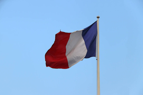 le tricolore vagy háromszínű francia zászló, le drapeau bleu-blanc-rouge vagy kék fehér és piros színű, kék ég háttér. Elfújta a szél.. - Fotó, kép