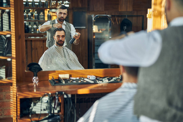 Skillful hair stylist having a client in his salon - Fotoğraf, Görsel