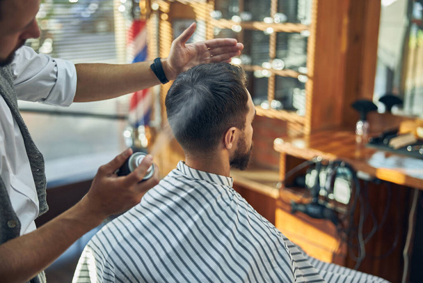 Barbiere professionista che utilizza qualche fissatore spray su un taglio di capelli fresco - Foto, immagini