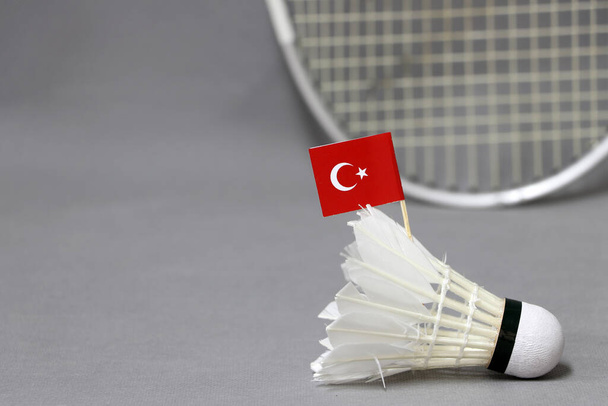 Mini Törökország zászló bottal a fehér shuttlecock a szürke háttér és ki fókusz tollaslabda ütő. A tollaslabda-sport fogalma. - Fotó, kép