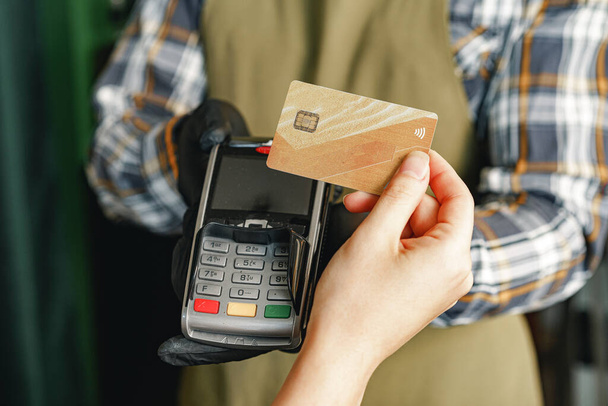 Klant gebruikt kredietkaart voor betaling in café of winkel per terminal met nfc cashless technologie - Foto, afbeelding