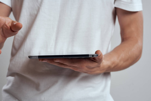 Tablet mit Touchscreen auf hellem Hintergrund männliche Hände weißes T-Shirt abgeschnitten Ansicht - Foto, Bild