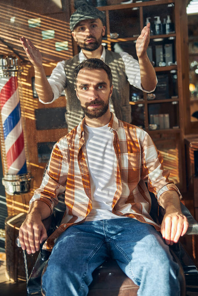 Stylish barber and hipster client posing at a barbershop - Fotoğraf, Görsel
