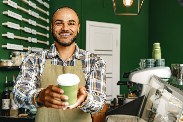 Portrait of a mixed race young man barista in coffee shop - 写真・画像