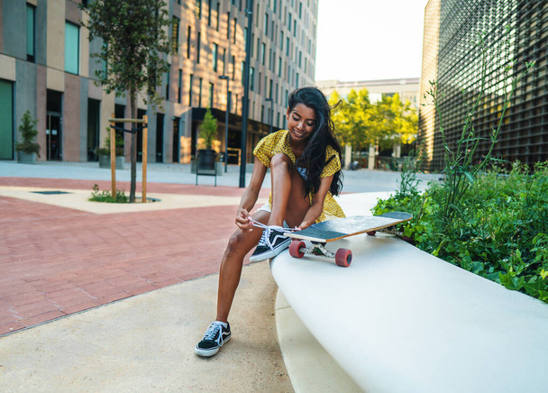 Güzel atletik kız modern şehirde uzun tahtasıyla oturuyor. - Fotoğraf, Görsel