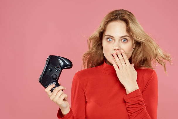 Woman with gamepad in hand entertainment video games lifestyle technology red blouse pink background - Photo, image
