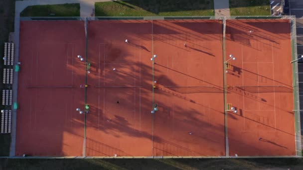 Skupina tenistů hraje ve večerním kurtu, letecký pohled - Záběry, video