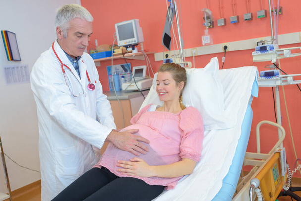 doctor examining pregnant lady touching bump - Fotoğraf, Görsel