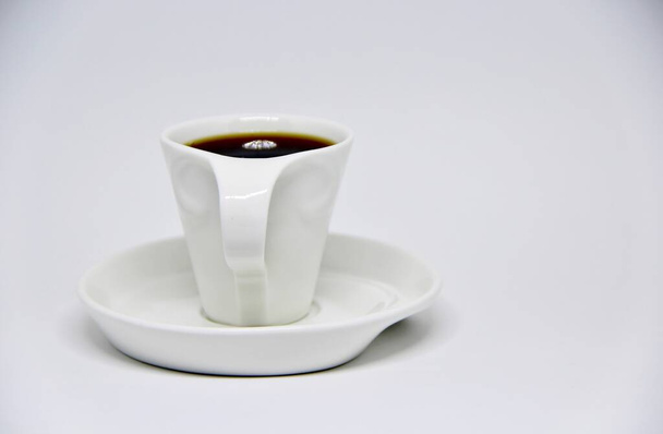 Widok pełnej filiżanki kawy na spodek w białym tle  - Zdjęcie, obraz