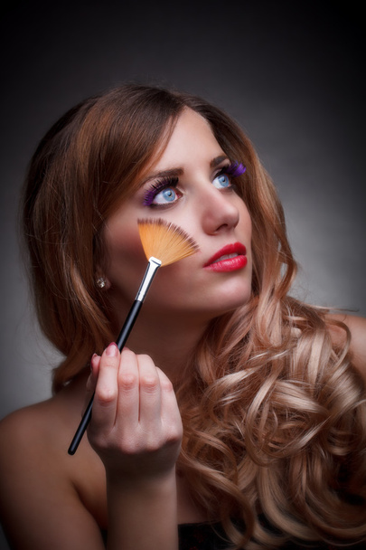 Молодая женщина с кистью для макияжа
 - Фото, изображение