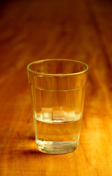 Veduta di un bicchiere mezzo pieno su sfondo di legno - Foto, immagini