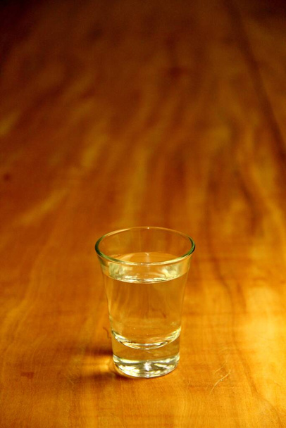 Blick auf ein halbvolles Glas auf Holzgrund - Foto, Bild