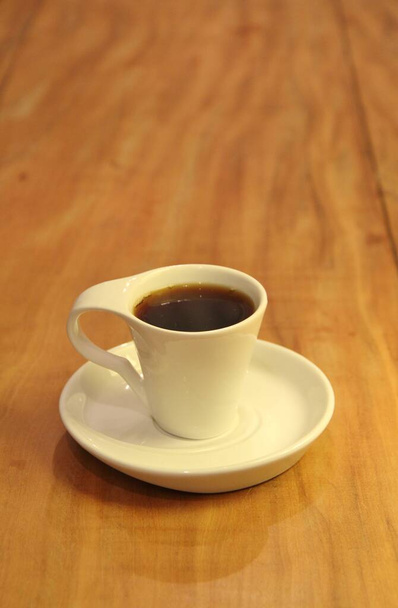 View of a full coffee cup on a saucer in wooden background - Photo, Image