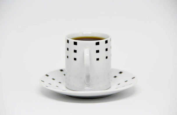 Vista de uma xícara de café cheia em um pires em fundo branco  - Foto, Imagem