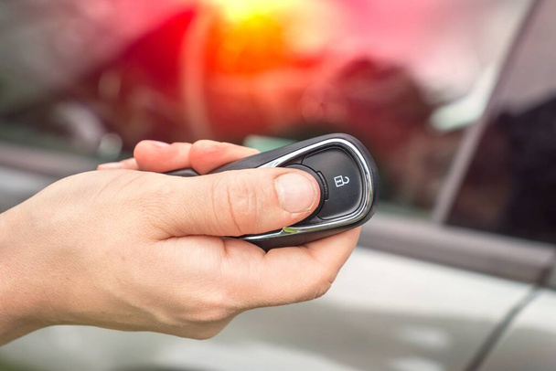 Woman lock or unlock her car with car remote control - car on background - Фото, изображение