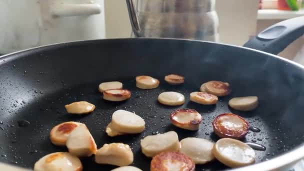 Deliciosas rebanadas de salchichas saltar en la sartén antiadherente en la cocina - Metraje, vídeo