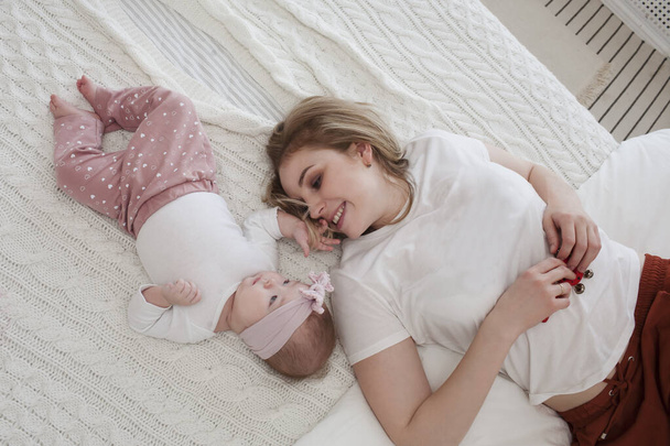 happy mom playing with newborn baby daughter and relaxing at home. parenthood concept - Fotó, kép