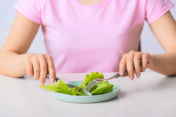 Vrouw die salade eet aan tafel, close-up. Concept van anorexia - Foto, afbeelding